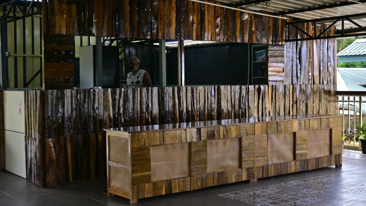 A reception area with a wooden reception desk and a person standing behind it.