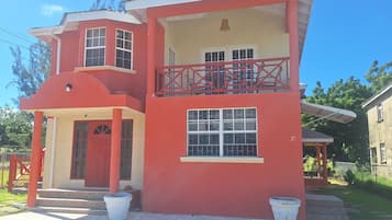 Un immeuble de deux étages avec une façade rouge, un balcon doté d’une balustrade rouge et le numéro « 37 » inscrit sur le côté.