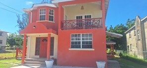 Un immeuble de deux étages avec une façade rouge, un balcon doté d’une balustrade rouge et le numéro « 37 » inscrit sur le côté.