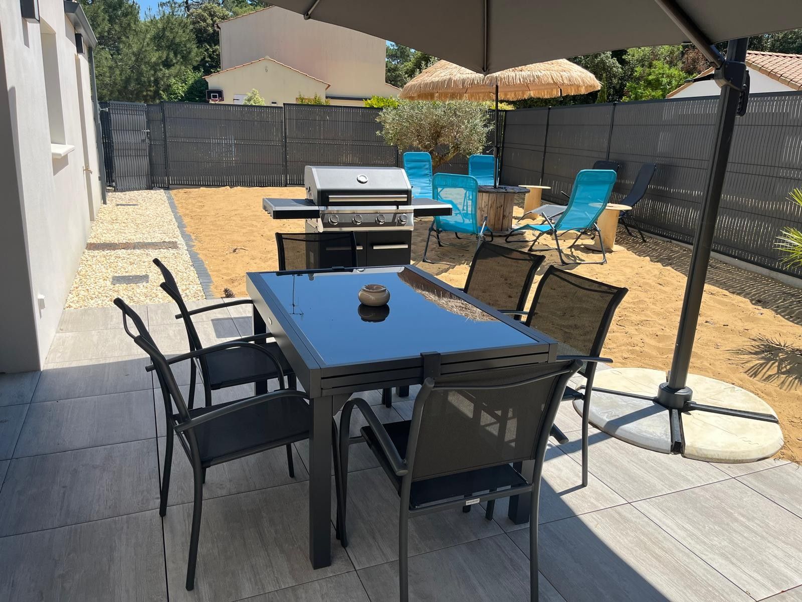 A patio with a table and chairs, a grill, and a covered seating area.