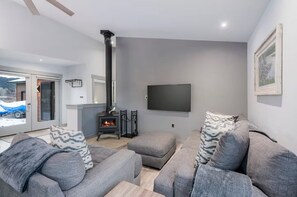 Una sala moderna con chimenea, sofás grises y un televisor de pantalla plana.