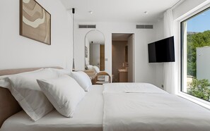 A hotel room with a large bed, a TV mounted on the wall, and a view of the outdoors. - Villa A, modern villa on a peaceful hillside in Podstrana (Podstrana)