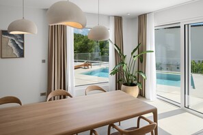 Bright dining area with direct access to the pool terrace, featuring solid-wood designer furniture by renowned brand Artisan, abundant natural light and views of the outdoor pool area. - Villa A, modern villa on a peaceful hillside in Podstrana (Podstrana)