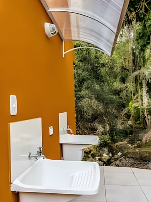 Un baño con lavamanos y bañera blancos, un espejo, e iluminación montada en la pared.