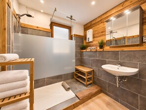 Ein modernes Badezimmer mit einem Holzkosmetikschrank, einem Waschbecken, einer Dusche und einem Spiegel.