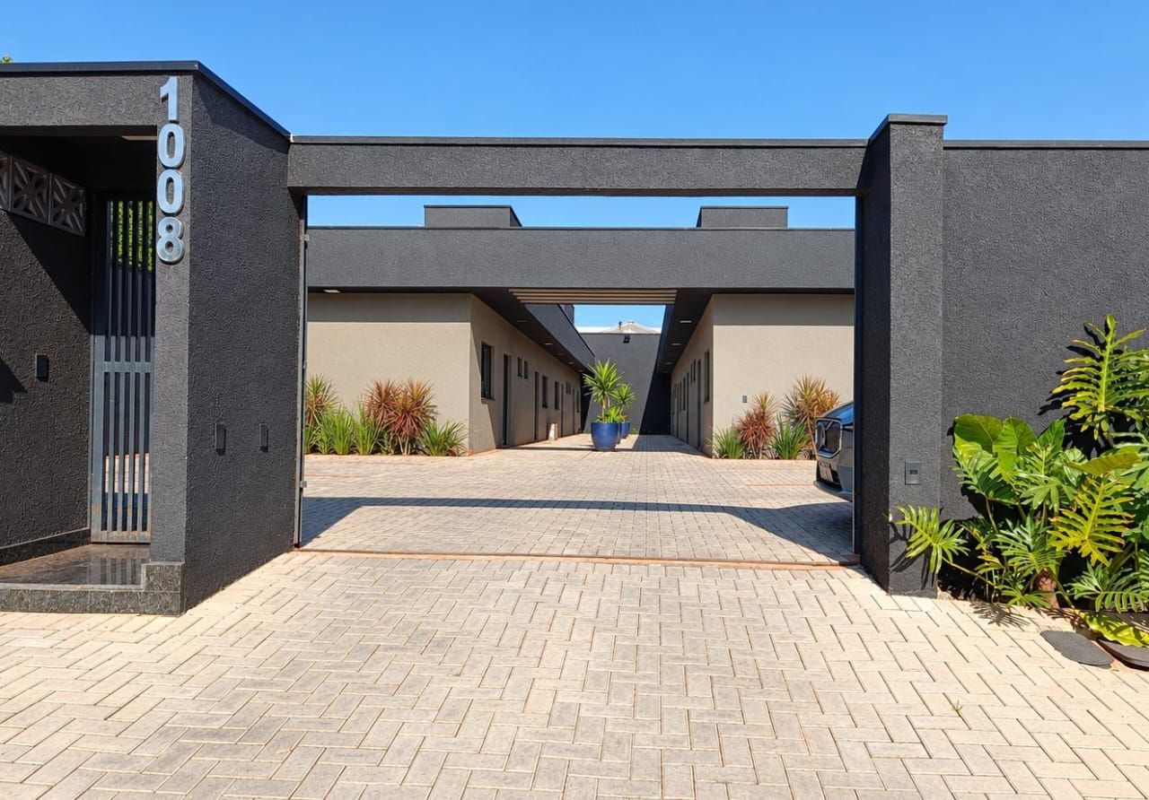 A modern building entrance with a paved pathway leading to a covered walkway.