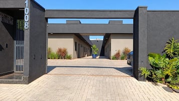 A modern building entrance with a paved pathway leading to a covered walkway.