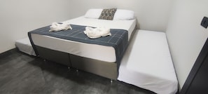 A single bed with a quilted headboard, a pillow, and two folded towels. - Studio 2 (Porto Rico)