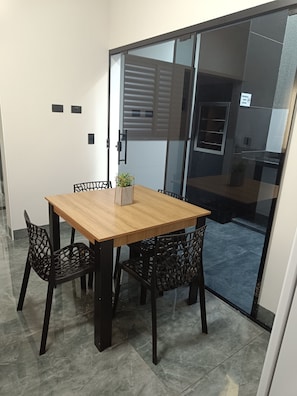 A room with a wooden table and chairs, a potted plant, and a sliding glass door leading to another area. - Studio 2 (Porto Rico)