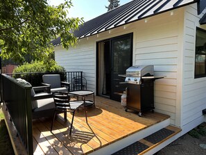 Een terras met een barbecue, tuinmeubilair en een schuifpui.