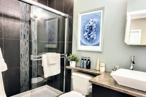 Un baño moderno con cabina de ducha de vidrio, inodoro blanco y lavabo con encimera.