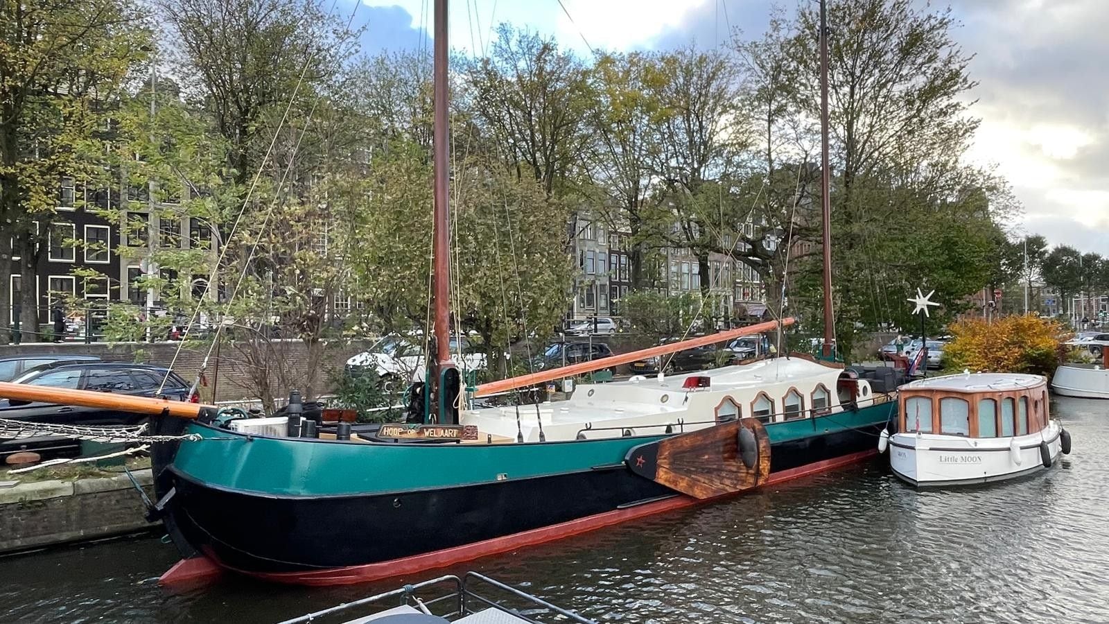 Ein Boot liegt in einer Marina vor einer Stadtlandschaft.