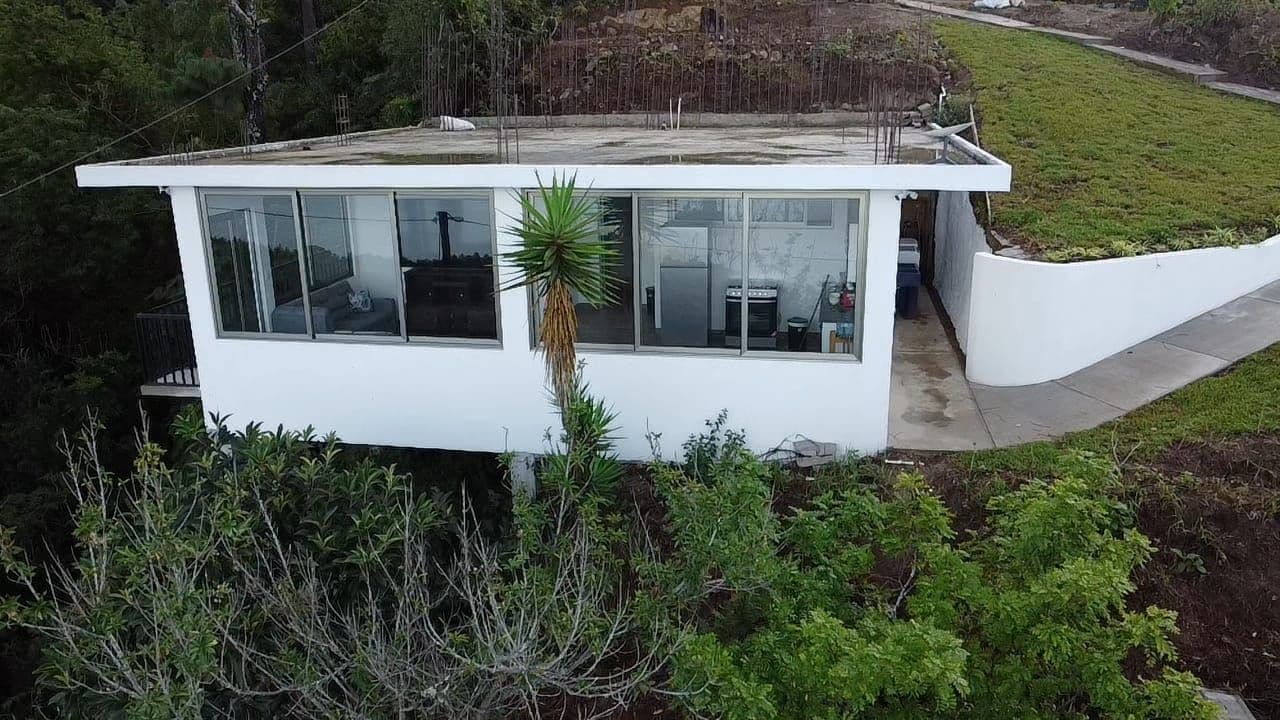 Una casa moderna de un piso con techo plano, ventanas grandes y un pequeño porche.