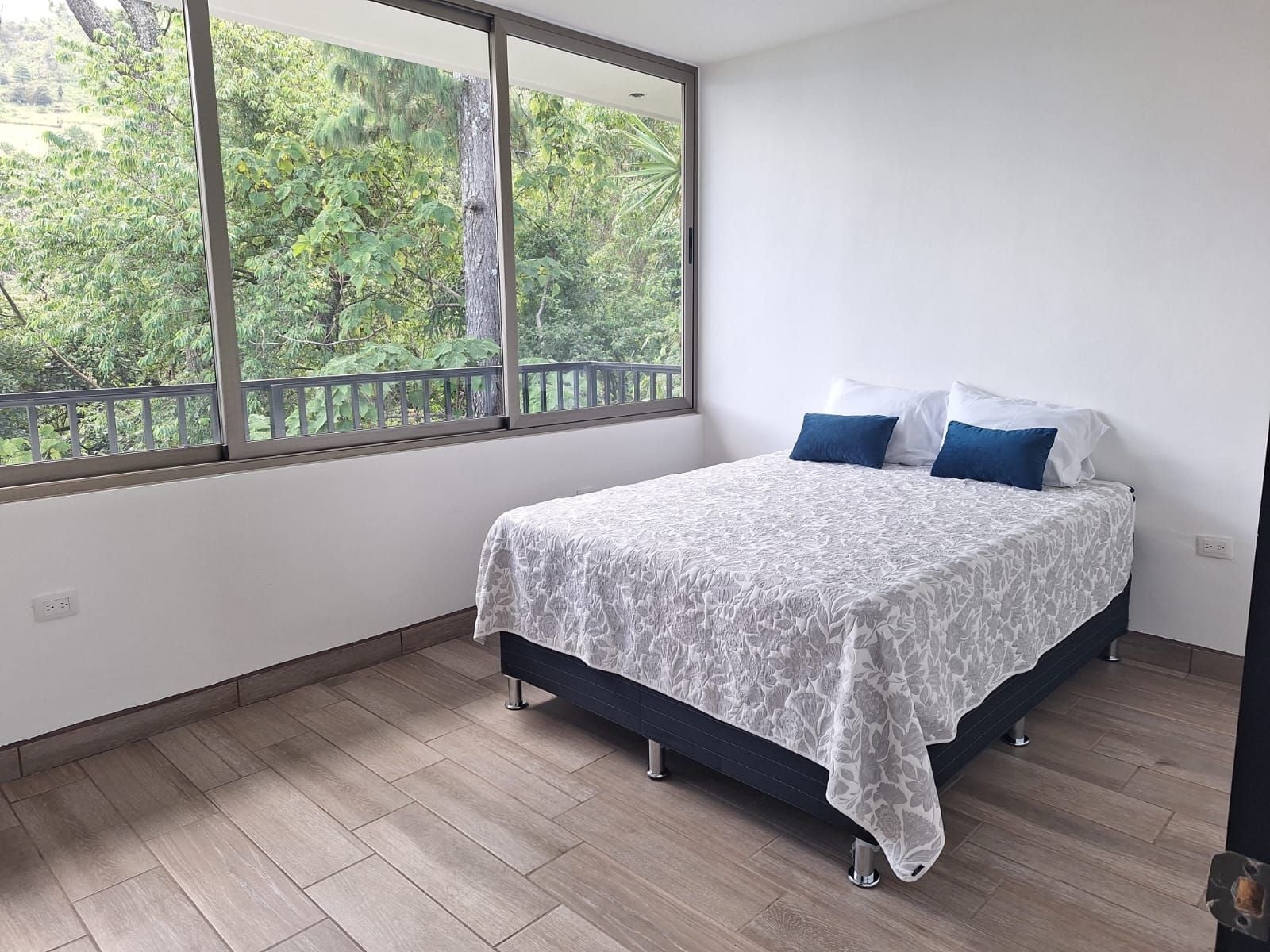 Un dormitorio con cama, ventana y vista a zonas verdes.