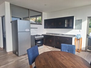 Una cocina moderna con horno empotrado, refrigerador y una mesa de comedor con sillas.