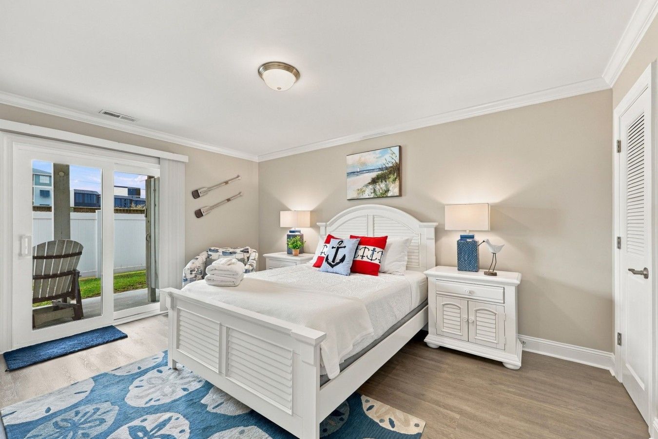 Een slaapkamer met een bed, nachtkastjes, een lamp, een stoel, een raam en een deur.