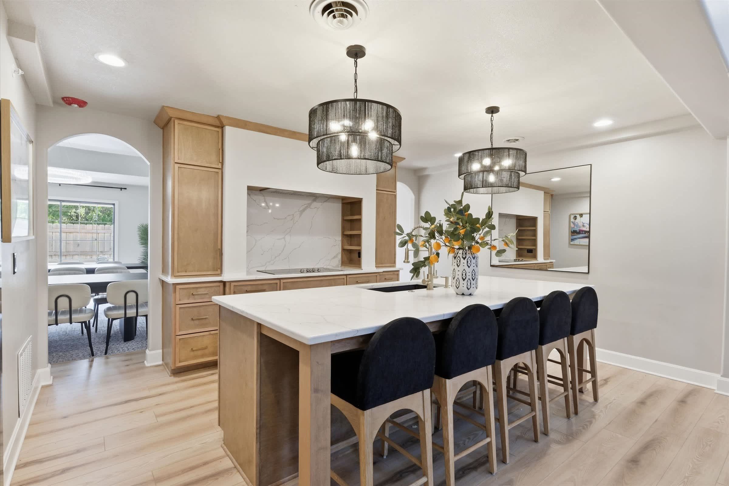 Una cocina moderna con una isla grande, armarios de madera e iluminación colgante.