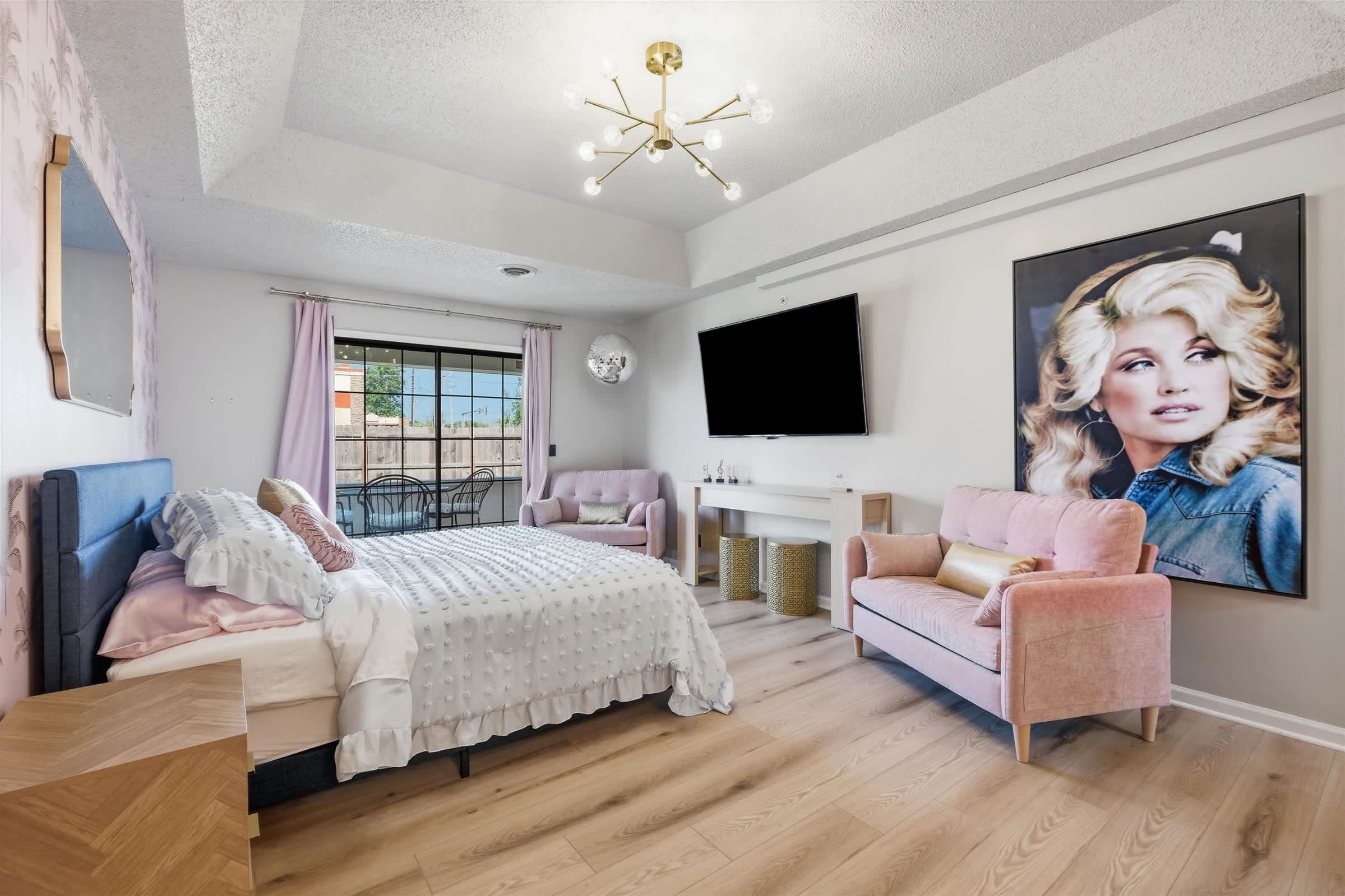 Un dormitorio con cama, sofá, televisión y un cartel grande en la pared.