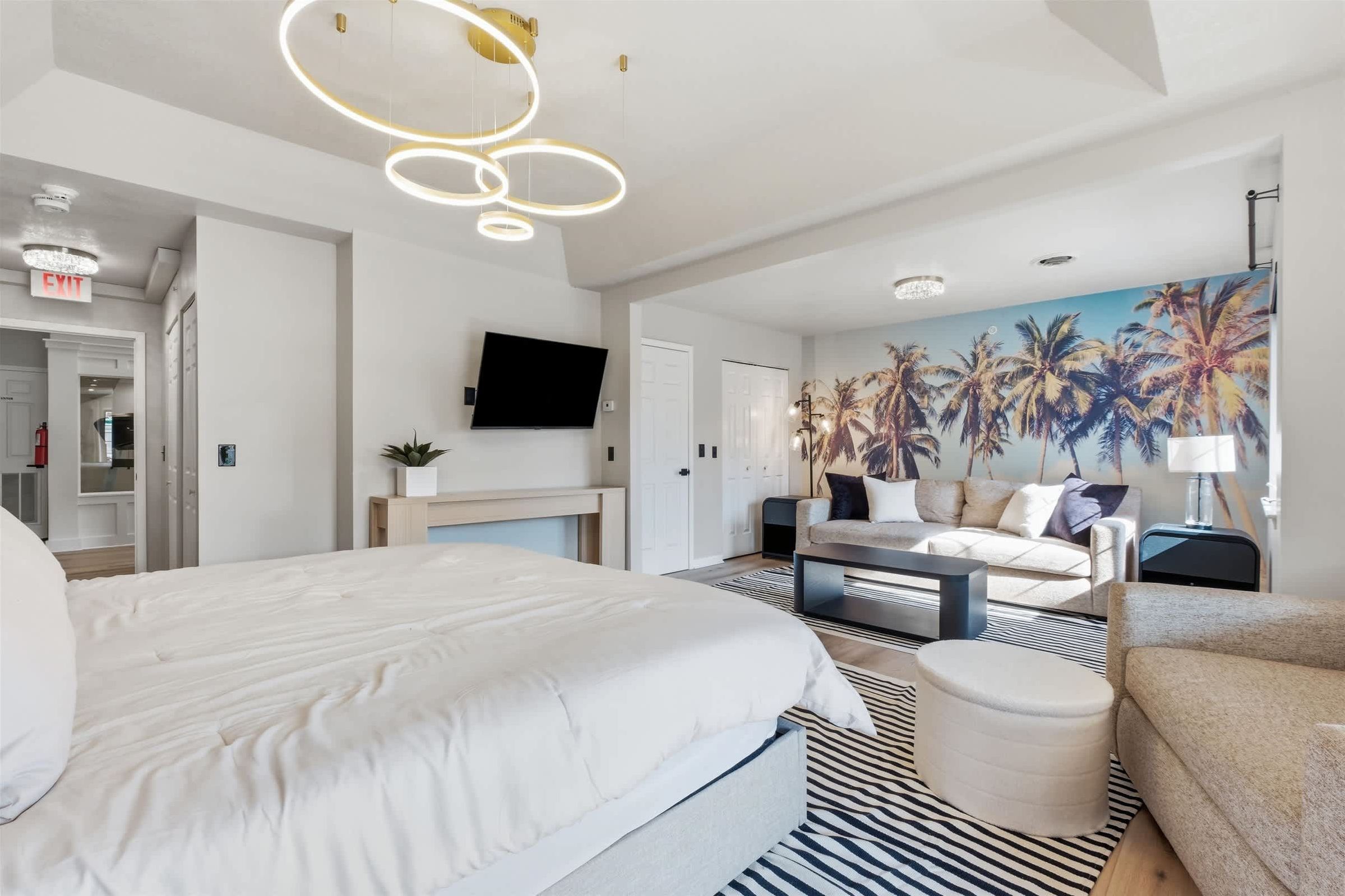 A modern hotel room with a large bed, a sofa, a coffee table, and a TV.
