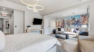 A modern hotel room with a large bed, a sofa, a coffee table, and a TV.