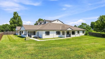 A single-story house with a covered porch, a fenced yard, and a clear blue sky.