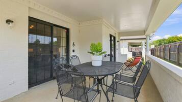A covered patio with a round table and chairs, a potted plant, and a view of the backyard.