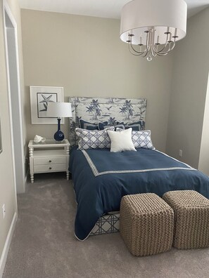 Ein Schlafzimmer mit einem Bett, einem Nachttisch, einer Lampe, einer Kronleuchter und einer Wand mit einem gerahmten Bild.