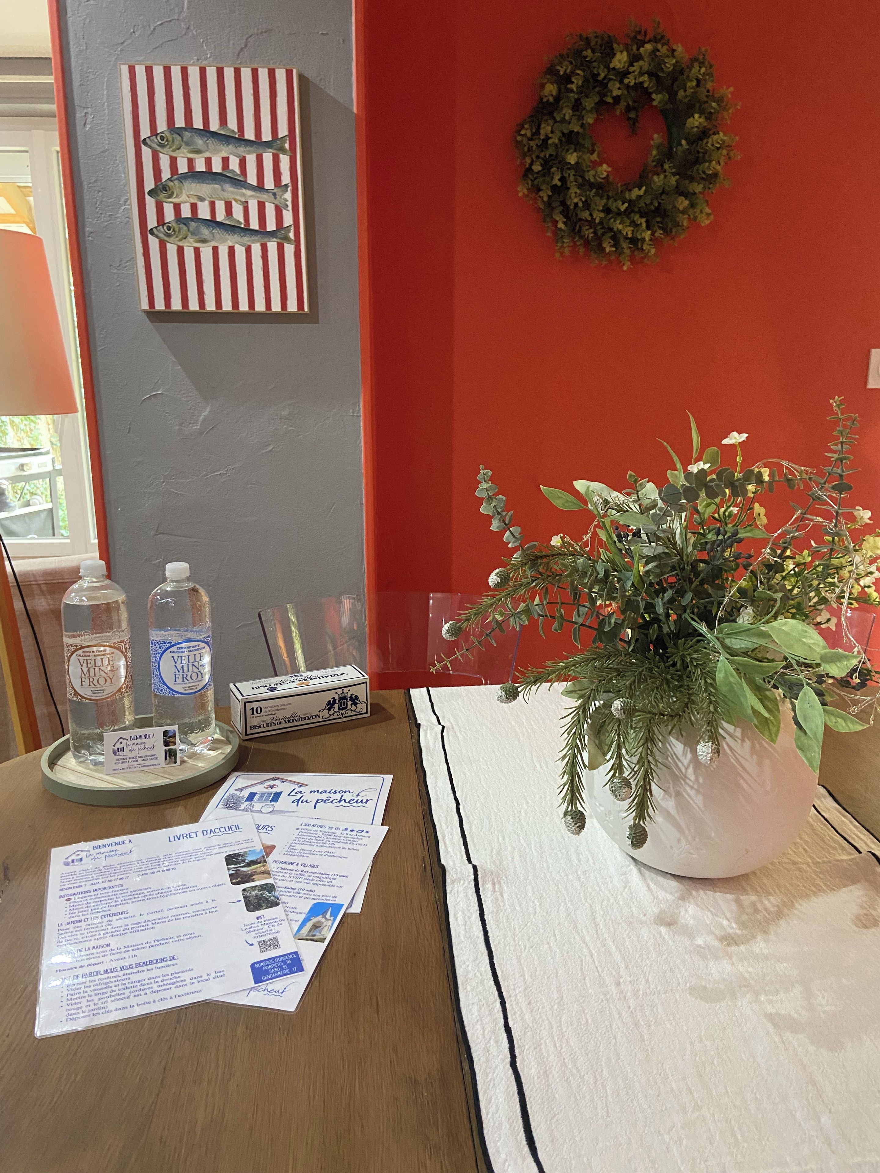 Une table avec une plante en pot, deux bouteilles d’eau, un menu et un panneau.