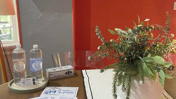 Une table avec une plante en pot, deux bouteilles d’eau, un menu et un panneau.