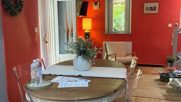 Un coin repas avec une table en bois, des chaises transparentes, un vase avec des fleurs et une lampe.