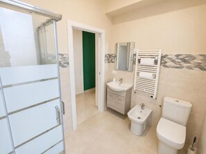 Une salle de bain équipée d’une douche, d’un lavabo, d’un bidet, de toilettes et d’un porte-serviettes.