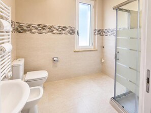Une salle de bain équipée de toilettes, d’un lavabo et d’une porte de douche en verre.