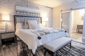 A bedroom with a bed, bedside tables, a bench, a patterned rug, and a sliding door. - Cozy 1-bedroom hotel suite in beautiful Seneca with AC - ROOM 4 (Seneca)
