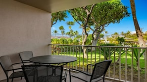A balcony with a round table and four chairs, overlooking a well-maintained garden with various trees and a clear blue sky. - Maui 3BR Villa at WorldMark Kihei – Full Kitchen, Balcony & Near Beach Access (Kihei)