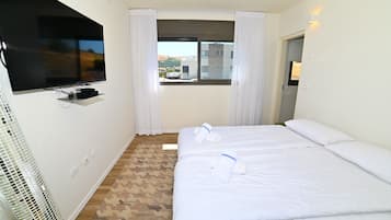 A hotel room with two beds, a television, and a window with curtains.