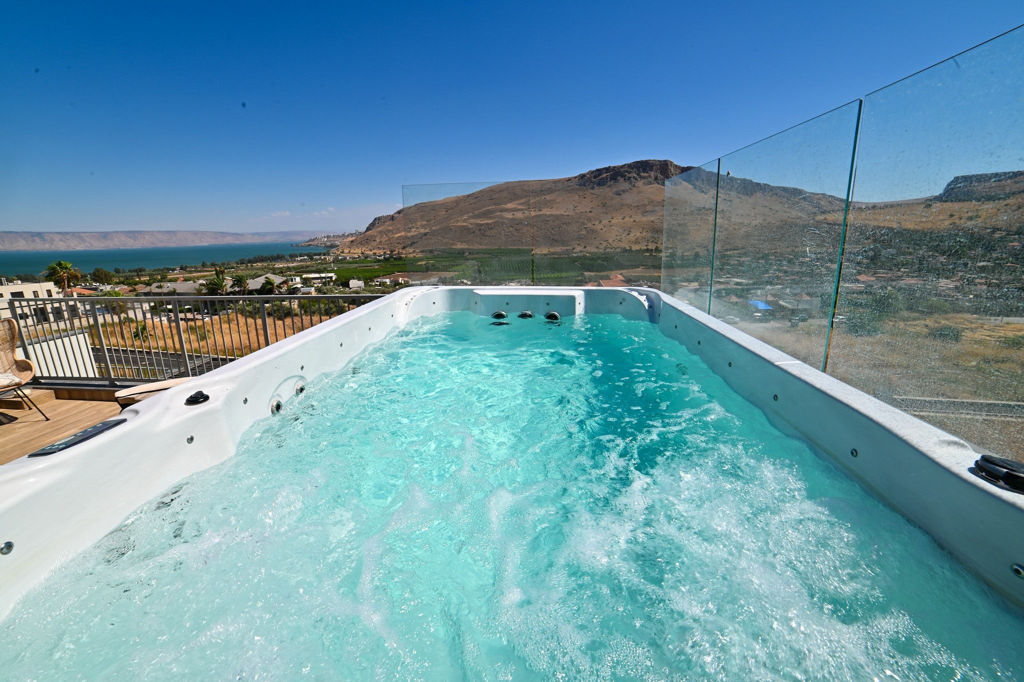 A hot tub with a clear view of the surrounding landscape, including a mountain and a body of water.