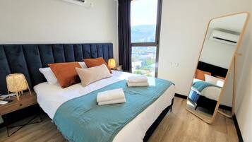 Een hotelkamer met een bed, nachtkastje, spiegel en een raam met uitzicht.