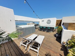 Een terras op het dak met een bar, lounge stoelen en uitzicht op zee.