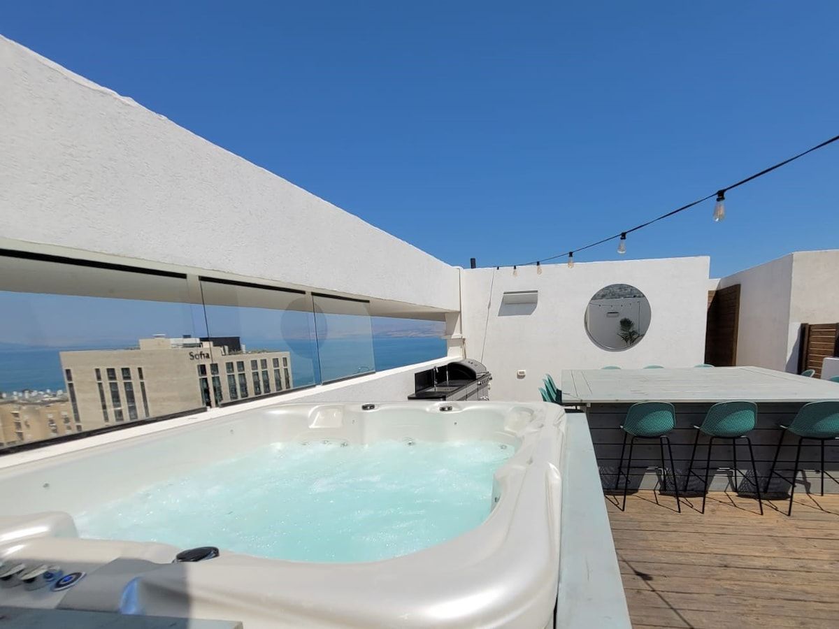 Een terras op het dak met een jacuzzi, buitenmeubels en een helder uitzicht op de stadshemel.