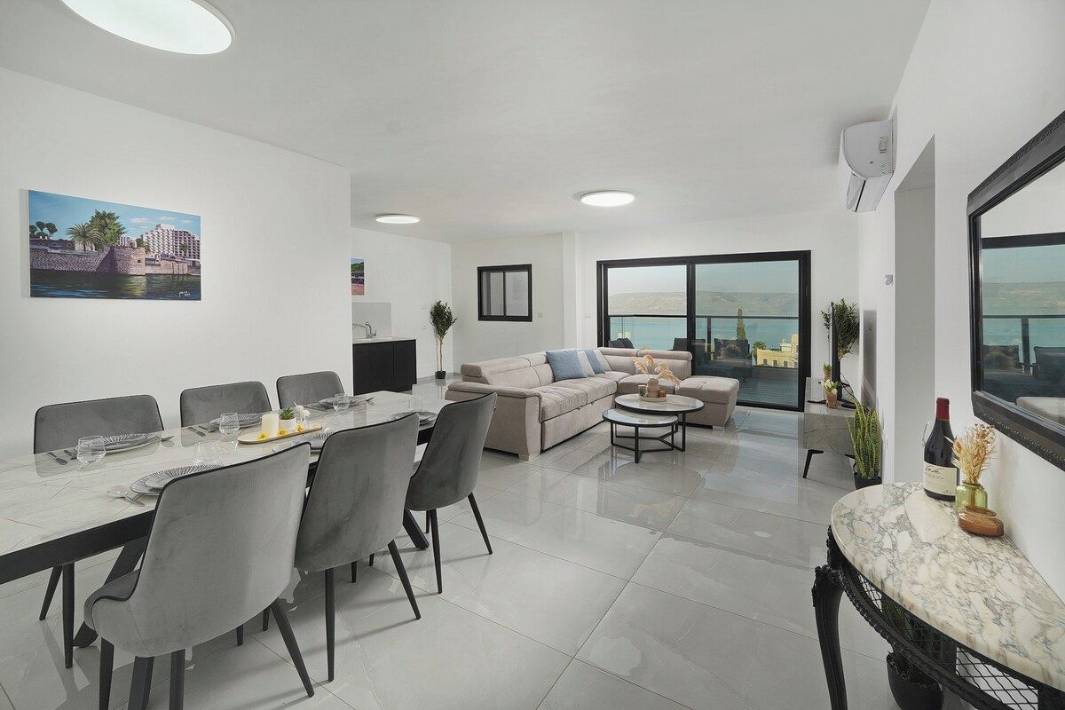 Een moderne woonkamer met een eethoek, een zithoek en een groot raam met uitzicht.