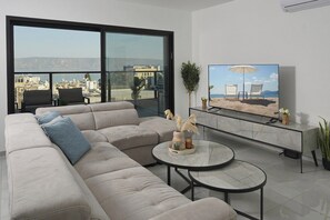Un salon moderne avec une grande fenêtre, un canapé, une table basse et un téléviseur à écran plat.
