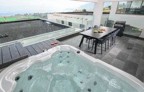 Une terrasse sur le toit équipée d’un jacuzzi, d’une table à manger, de chaises et d’un barbecue.
