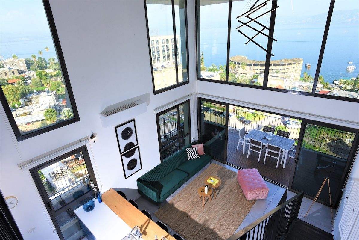 Een hoog appartementencomplex met balkon, grote ramen en uitzicht op de stad en zee.