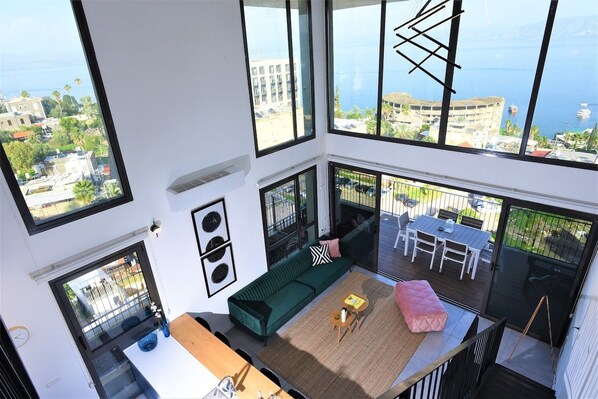 Een hoog appartementencomplex met balkon, grote ramen en uitzicht op de stad en zee.