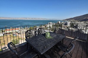 Un balcon avec une table et des chaises donnant sur un paysage urbain le long de la côte.