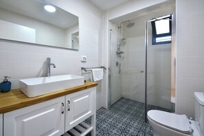 Une salle de bain avec un lavabo blanc, un miroir et une douche.