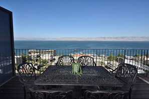 Un balcon avec une table et des chaises donnant sur une vue sur la côte.