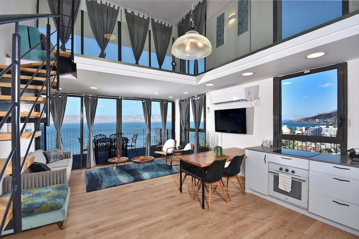 Een modern interieur met een eethoek, keuken en een groot raam met uitzicht op zee.