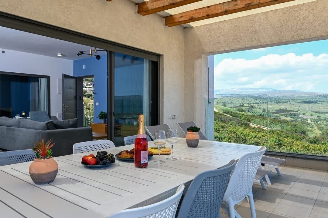 Comedor con una mesa preparada para dos personas, una botella de vino tinto y un plato de comida.
