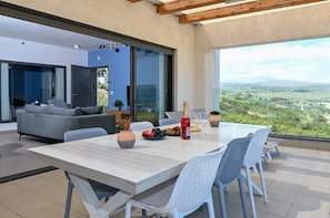 Una sala de estar moderna con un sofá, una mesa de comedor con sillas y vistas al campo.